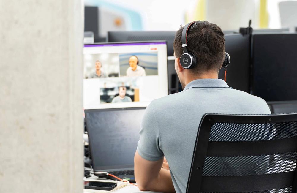 A male C5 Team member holds a teams call with clients on his laptop at his desk