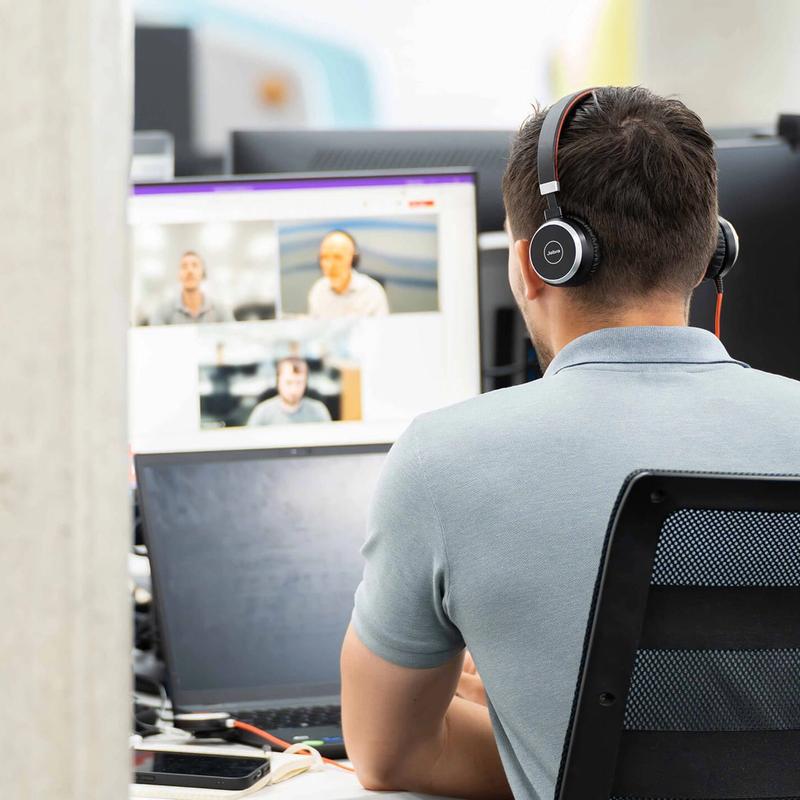 A male C5 Team member holds a teams call with clients on his laptop at his desk