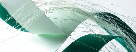 An abstract image of green and white strips of material mixed with what looks like strand of wool, depitcing a 'Data Fabric'