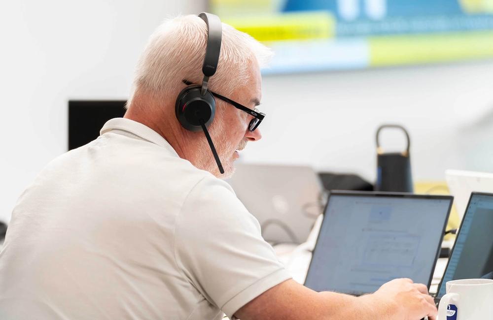 A C5 Team Member working on his laptop and additional monitors at his desk in the office
