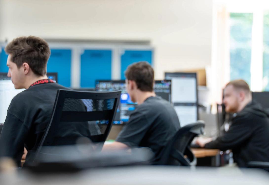 Several IT Services C5 Team Members working on their laptops and additional monitors at their desks in the office