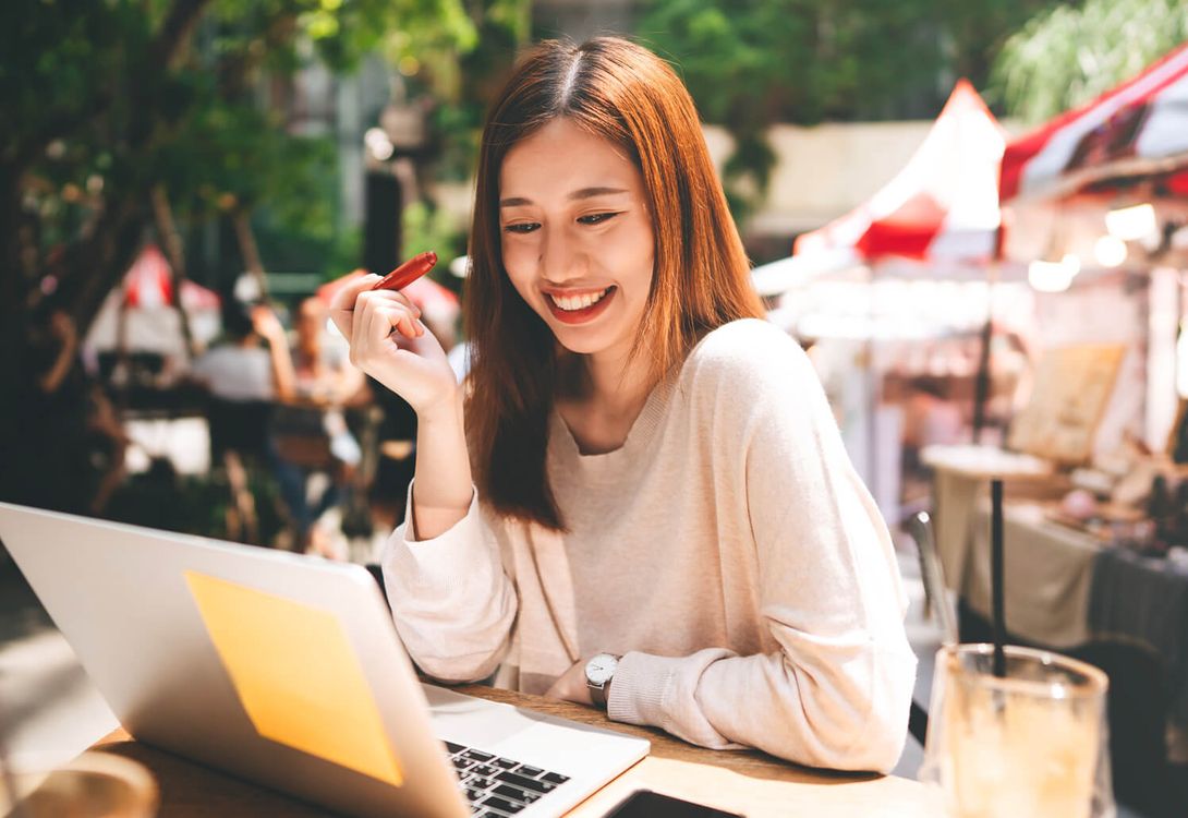 A photo of a young businesswoman working on her laptop at an outdoor café