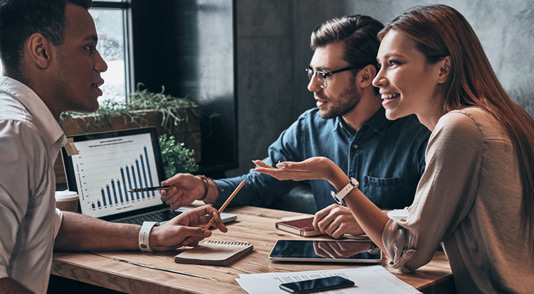 A group of people using Microsoft Power BI to discuss a technical solution to their business problems.