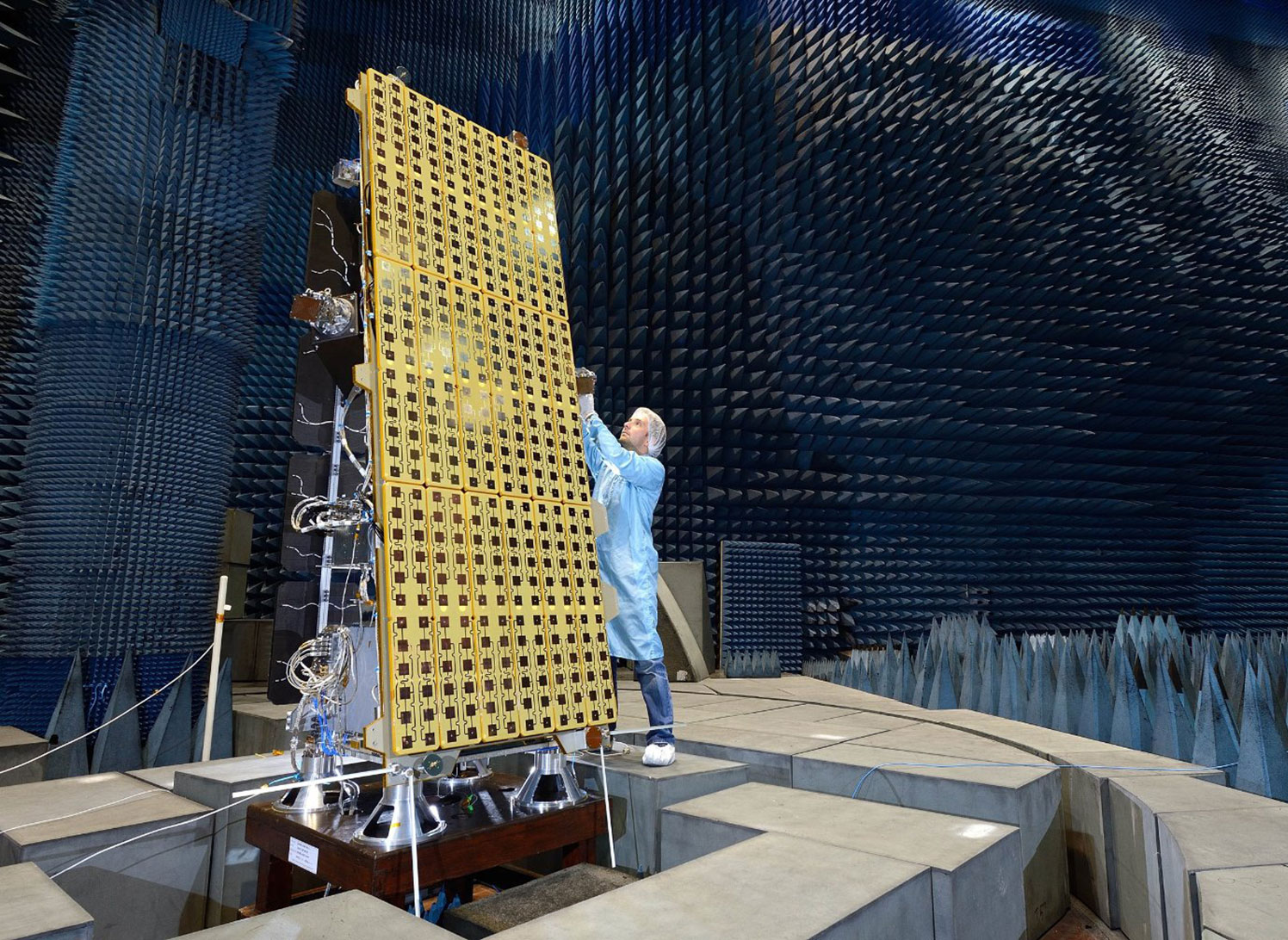 Surrey Satellite Technology - A man standing next to a satellite in a test laboratory